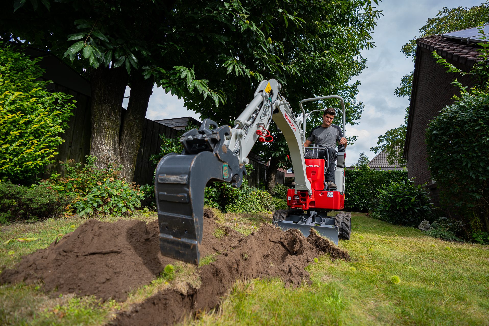 Hovenier op minigraver in tuin