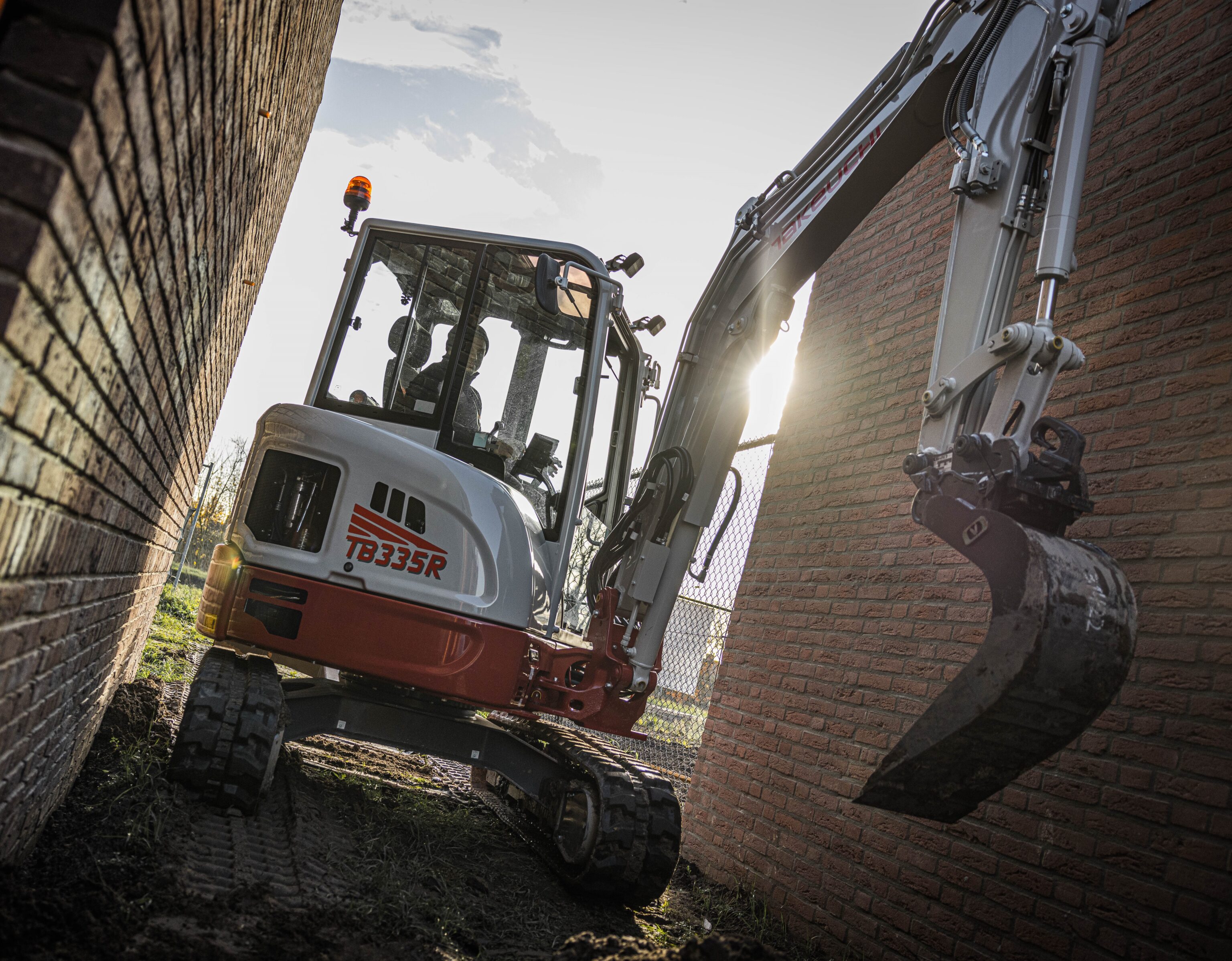 Takeuchi TB335R graafmachine rijdt door een smalle doorgang
