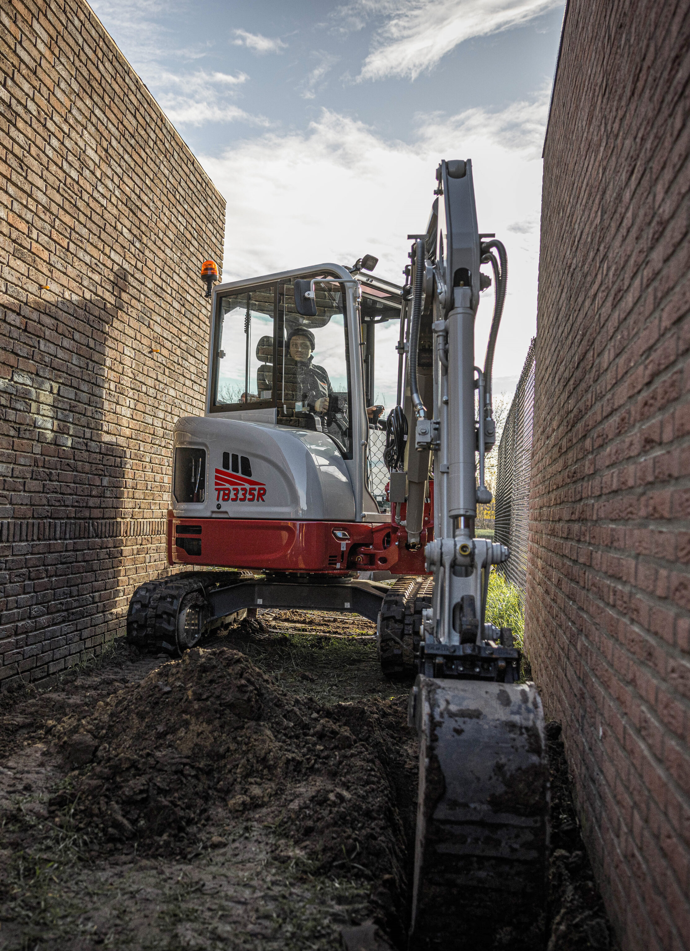 Takeuchi TB335R graafmachine graaf een sleuf strak langs een muur