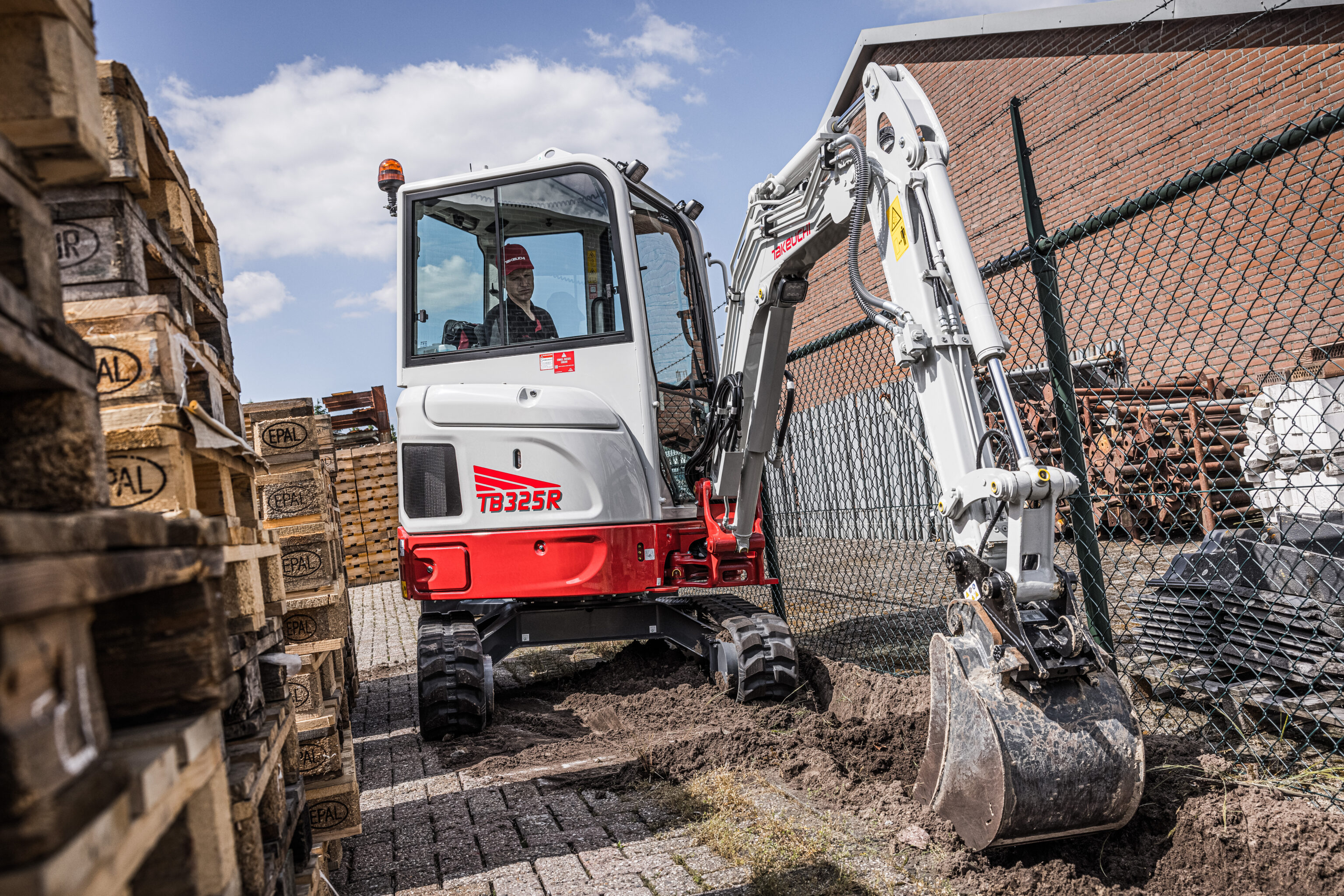 Travaux d’excavation avec la Takeuchi TB325R le long d’une clôture