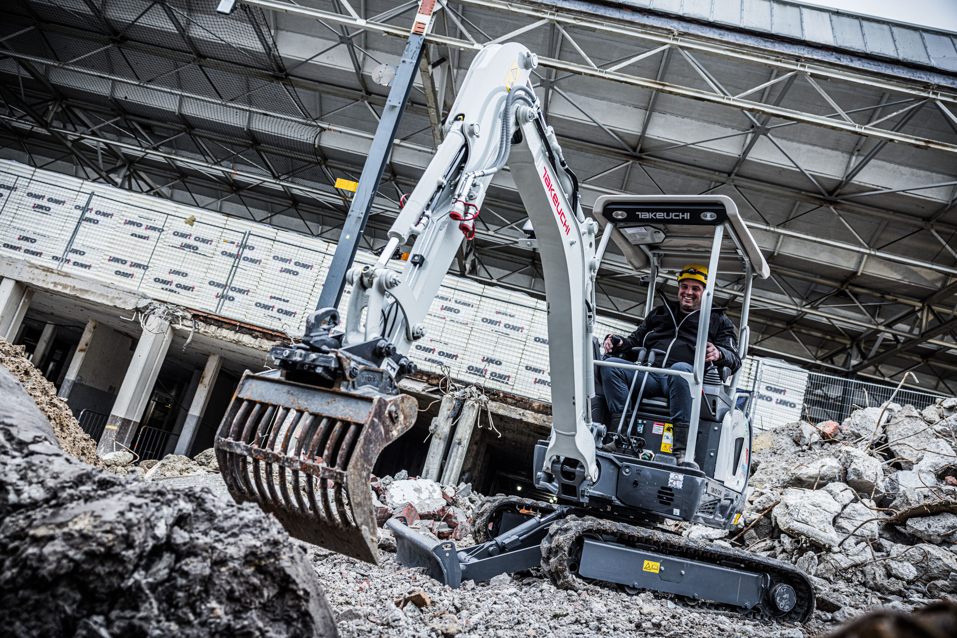 Takeuchi graafmachine met een puinbak bezig op een sloopterrein